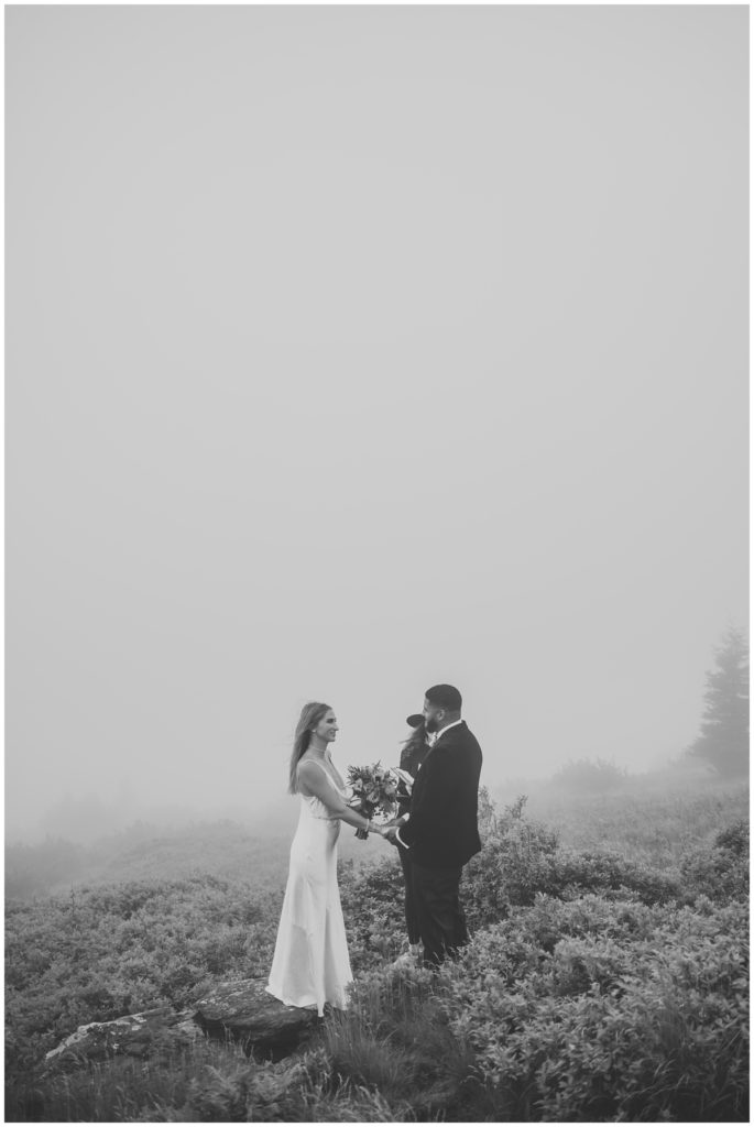 bride and groom during wedding ceremony in foggy mountain 