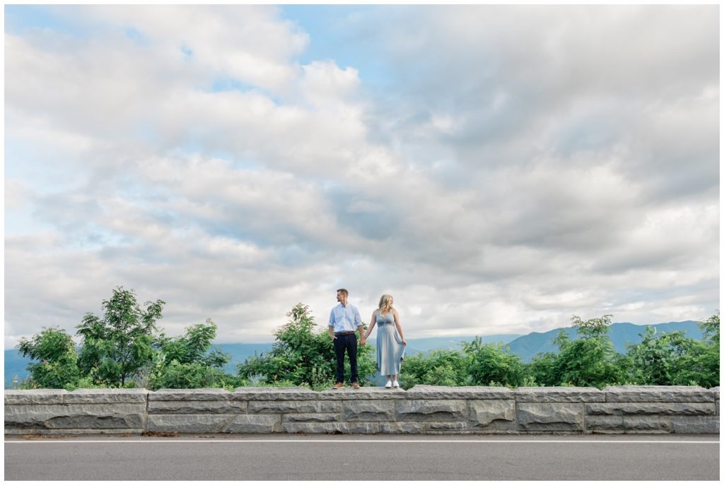 Man and woman standing on wall in Smoky Mountains looking in opposite directions