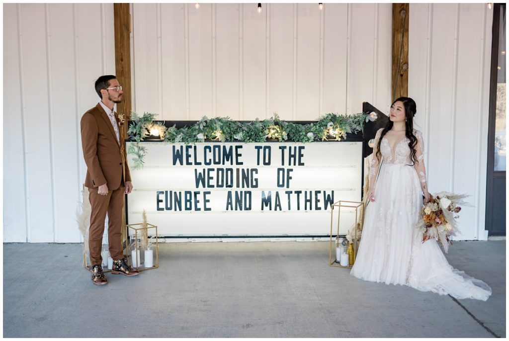 bride and groom in front of their wedding sign