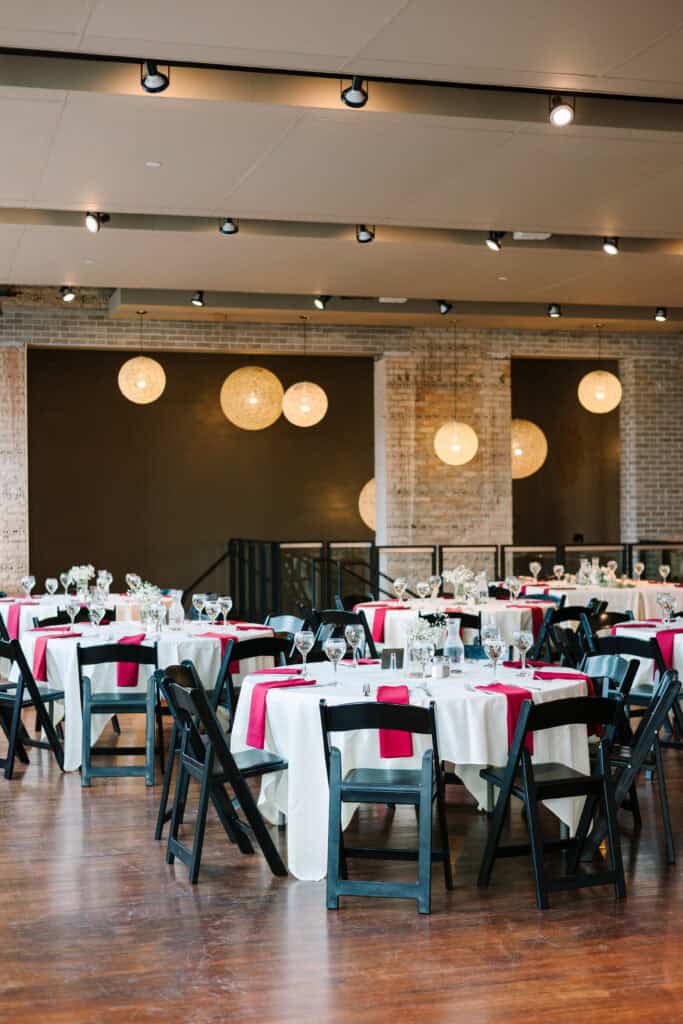 Olivia + Andrew Wedding Reception tables set with black linens and red accents at FIVE Event Center