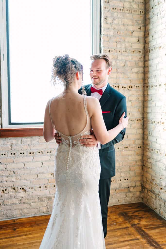 Olivia + Andrew Wedding Bride and groom embracing beside a large industrial window
