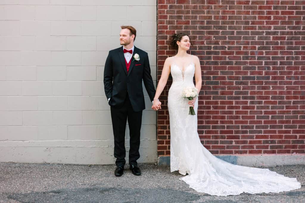 Olivia + Andrew Wedding Newlyweds posing together against a red brick wall in Minneapolis