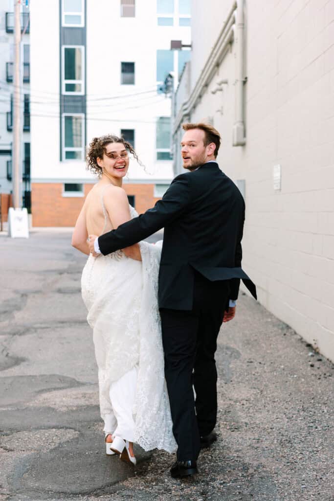 Olivia + Andrew Wedding Groom guiding the bride by the hand during downtown wedding portraits