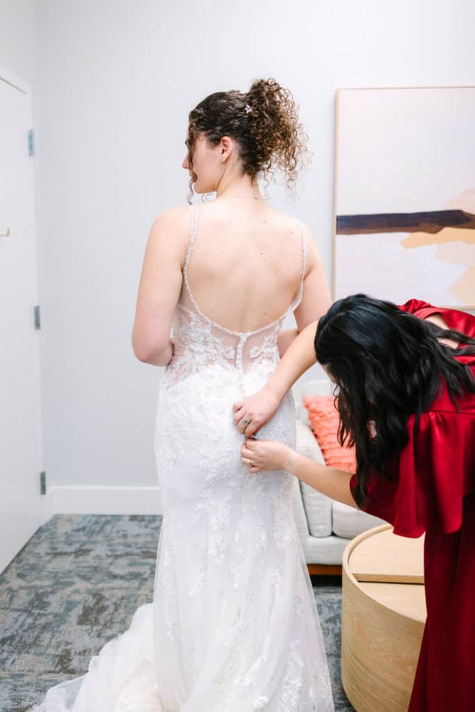Olivia + Andrew Wedding Bridesmaid adjusting the bride's wedding gown before the ceremony