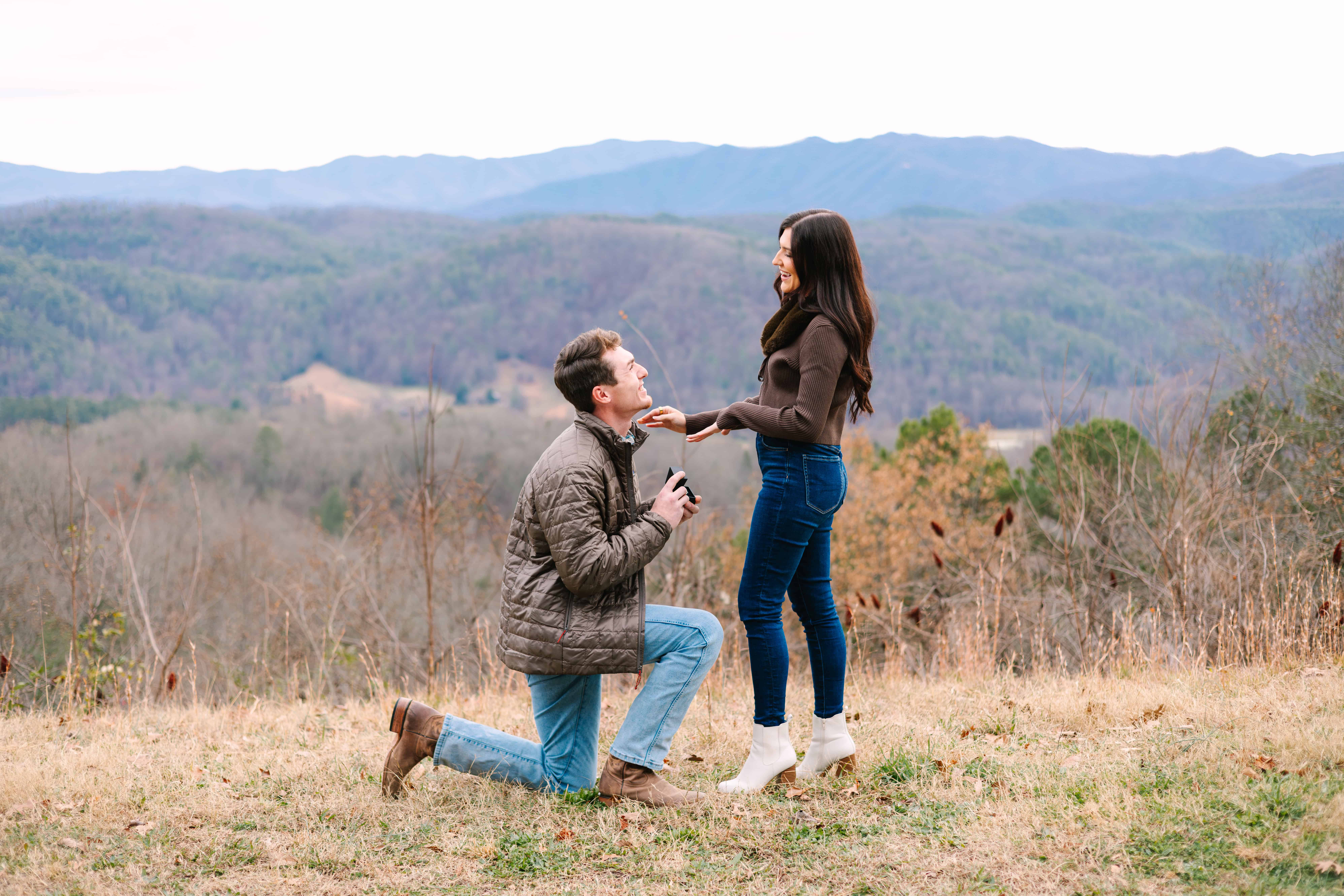 Newly engaged couple kissing and showing the engagement ring