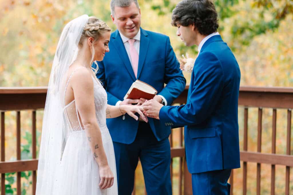 Bride and groom exchanging rings while the officiant holds their ceremony book