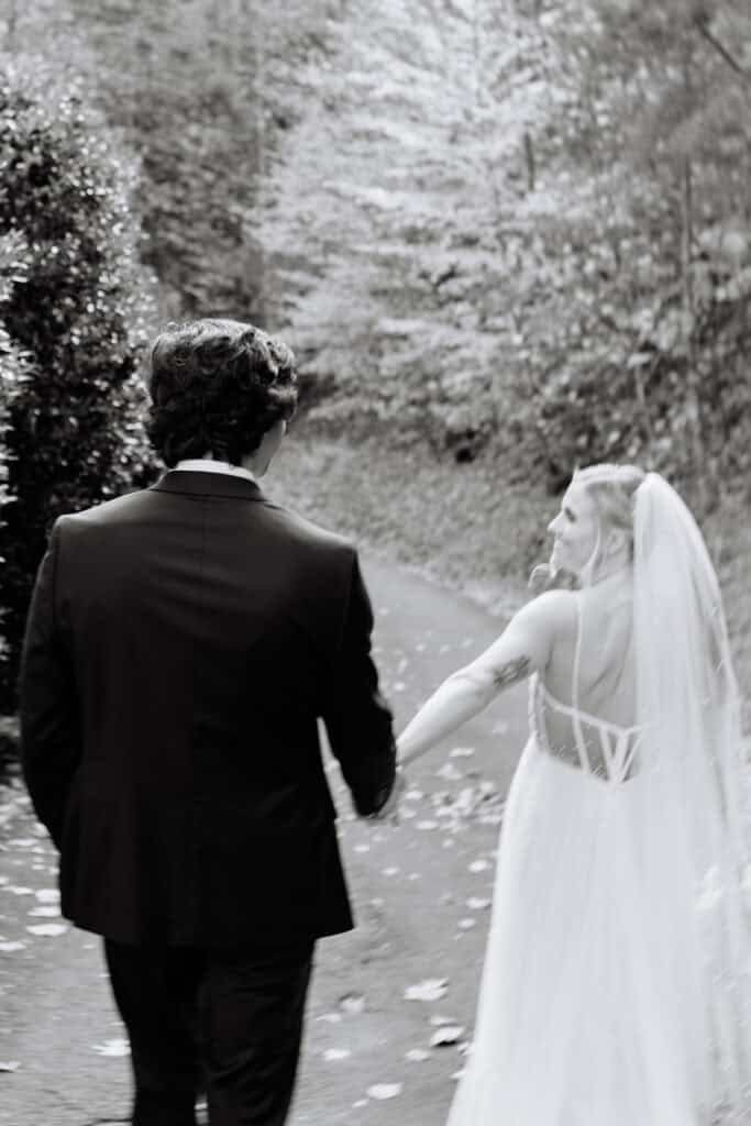 Black and white portrait of the bride approaching the groom for their first look