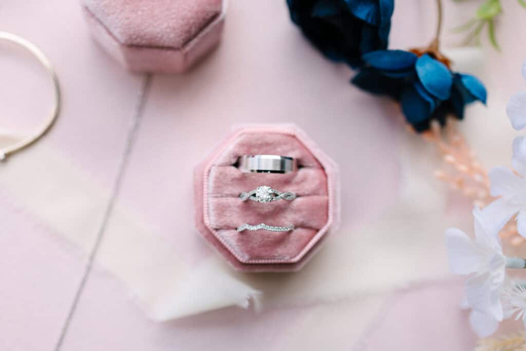 Three wedding rings displayed in a blush velvet ring box