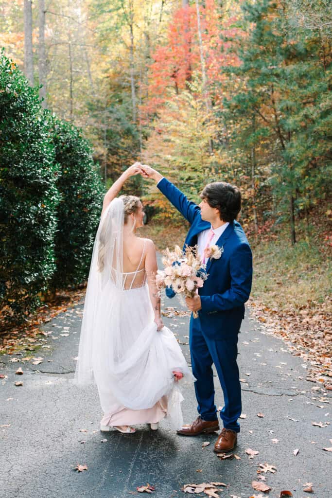 Bride and groom smiling at each other on a tree-lined path in the fall