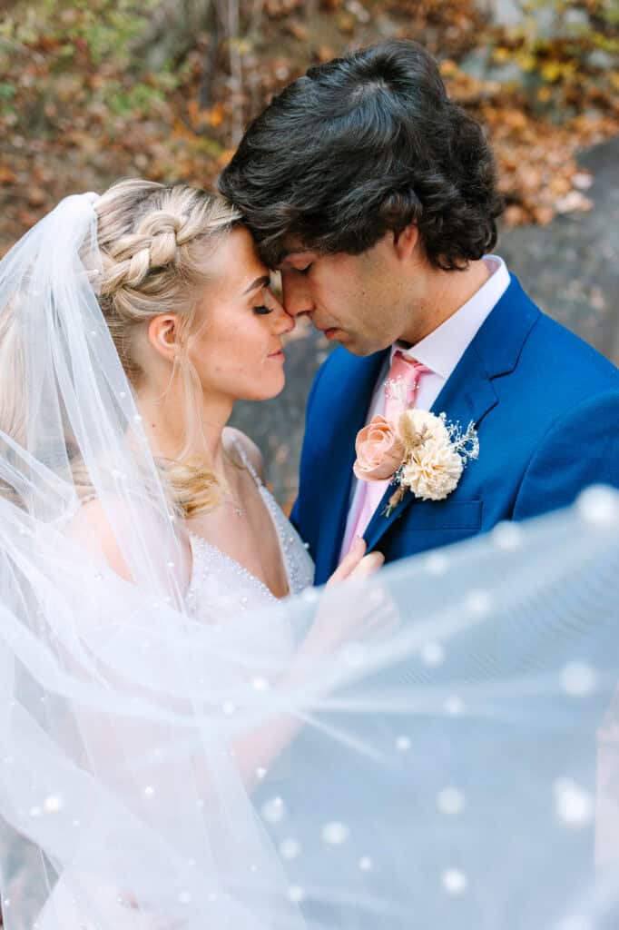 Bride and groom kissing beneath her veil during their fall microwedding