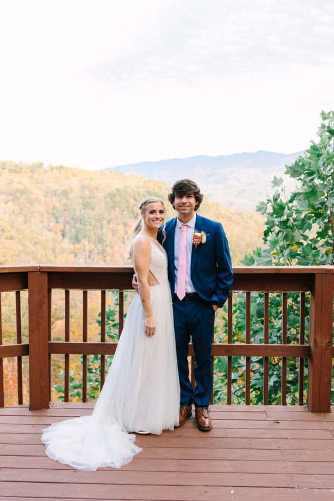 Bride and groom smiling together on a deck overlooking the Smoky Mountains