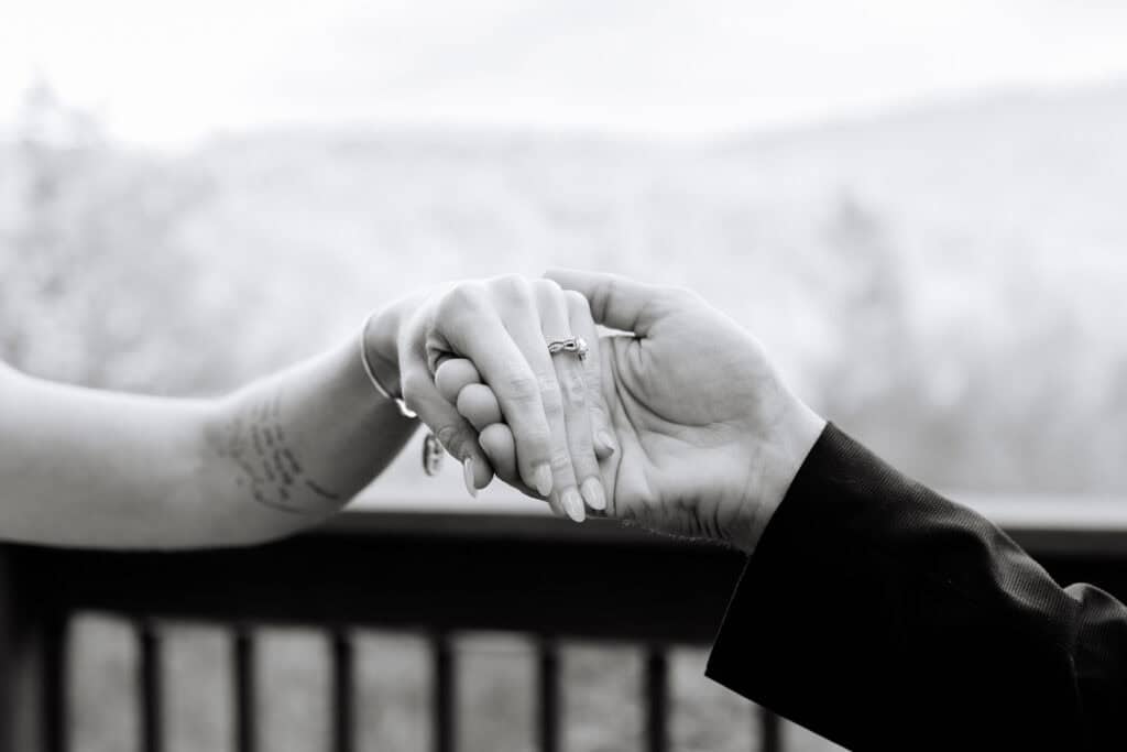 Black and white close-up of the bride and groom holding hands