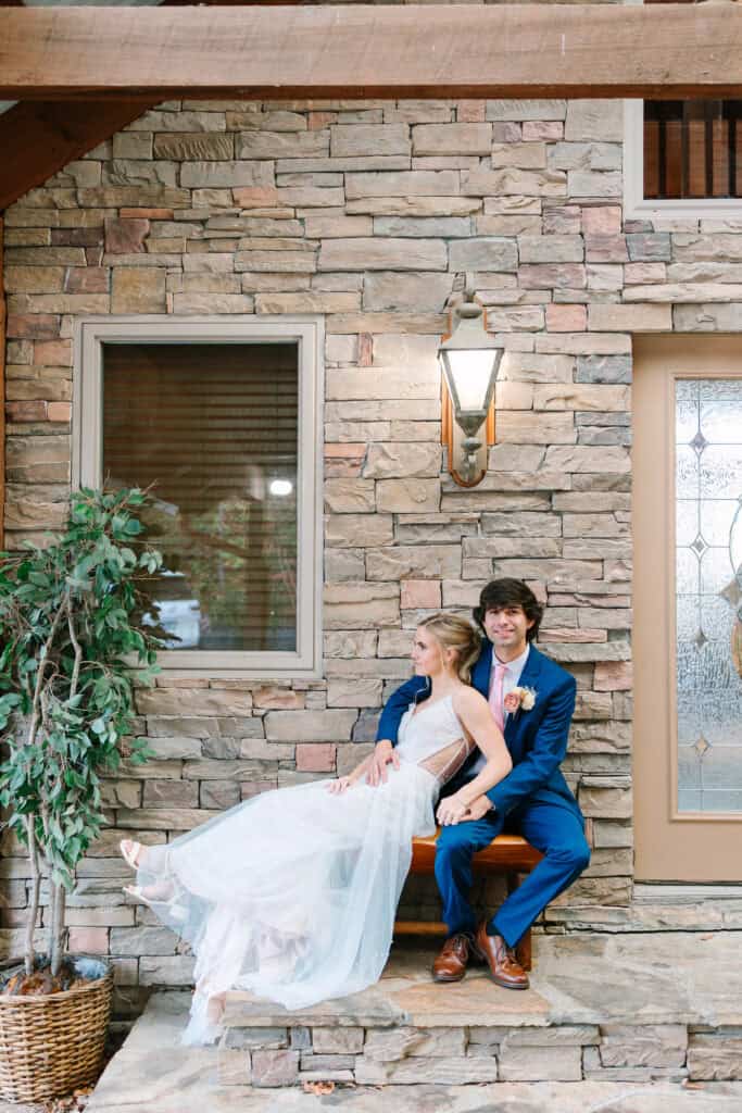 Bride and groom seated together on the stone steps of their cabin