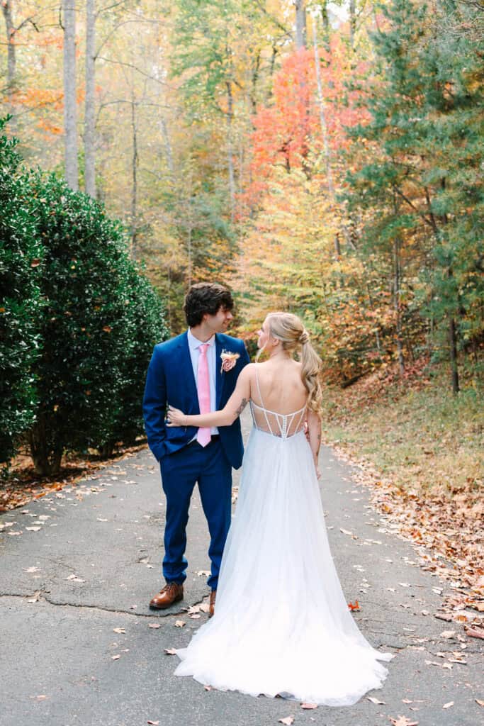 Bride and groom walking hand in hand along a wooded fall path