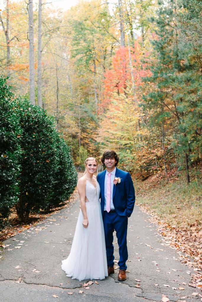 Bride and groom walking together toward the camera on a tree-lined path