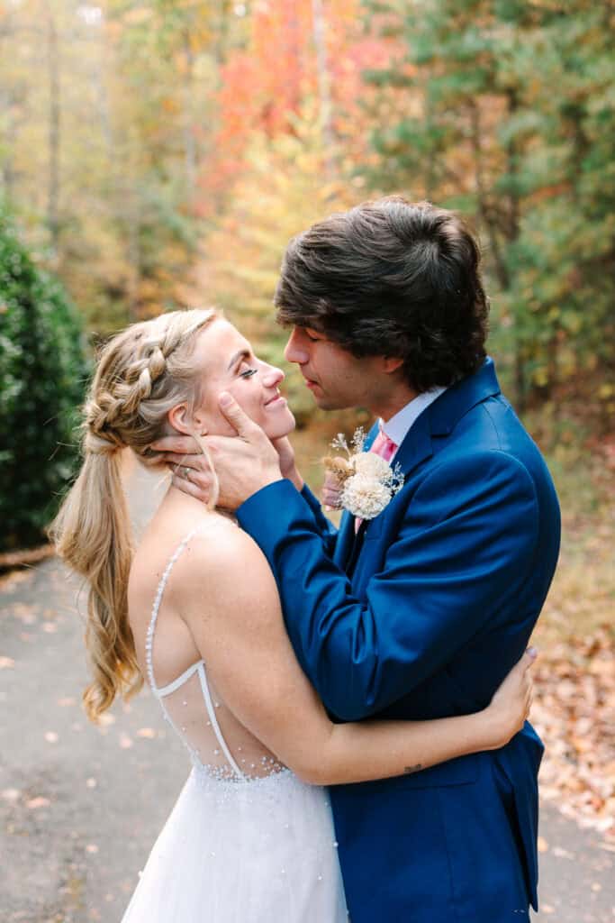 Groom holding the bride's face as they kiss during their fall portraits
