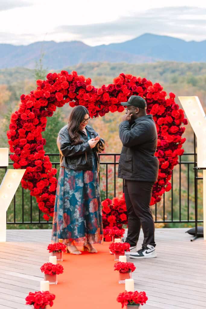 Bobby + Alyssa Proposal Woman reacting as her partner proposes beneath a red rose heart