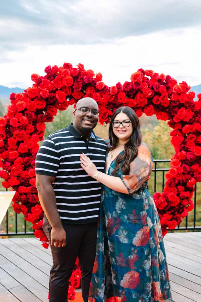 Bobby + Alyssa Proposal Newly engaged couple posing beside a rose heart in the Smoky Mountains