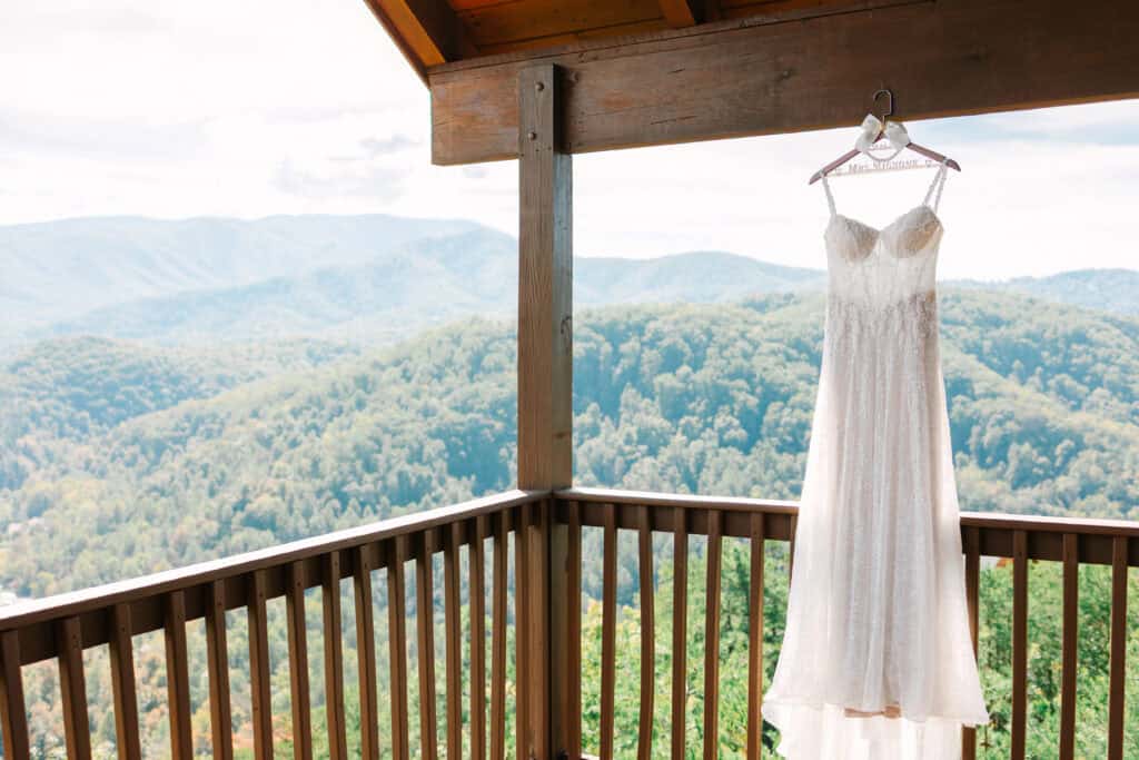 Lauren + Connor Wedding Wedding dress hangs from a cabin balcony at The Magnolia Venue