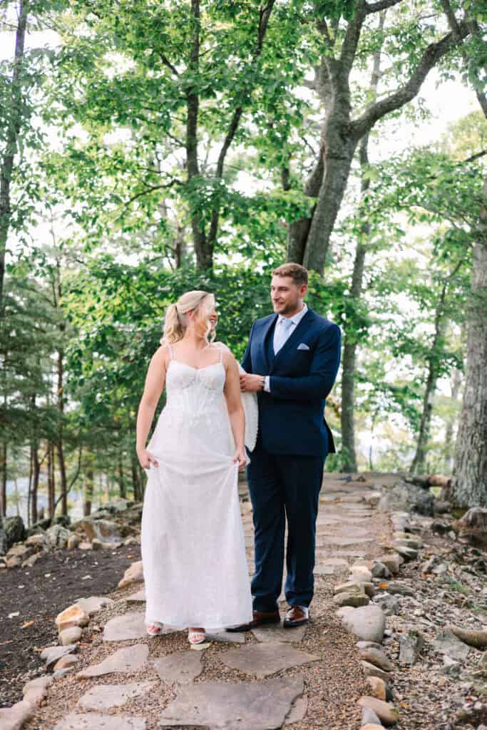 Lauren + Connor Wedding Bride adjusts the groom's navy bow tie among the trees