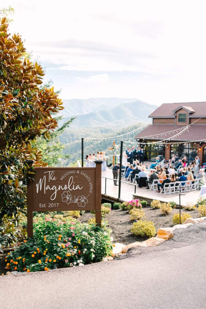 Lauren + Connor Wedding Magnolia welcome sign beside the outdoor ceremony and mountain view