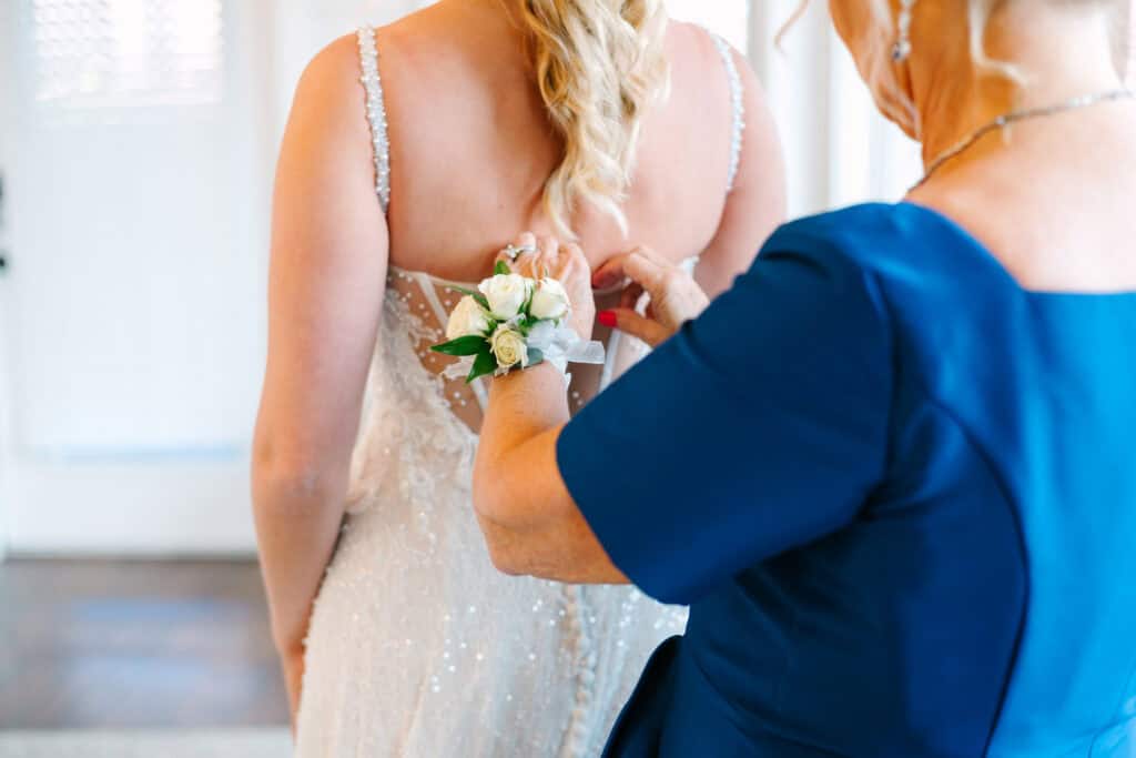 Lauren + Connor Wedding Bride's mother helps fasten a white floral corsage on her wrist