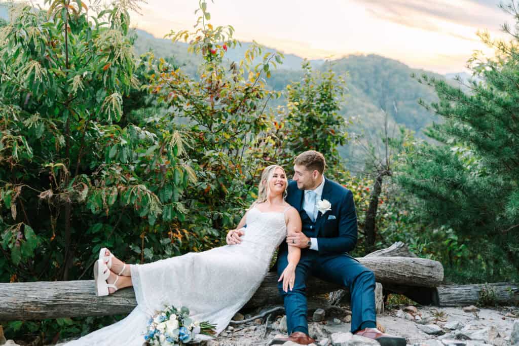 Lauren + Connor Wedding Bride reclines beside the groom on a fallen log at the mountain overlook