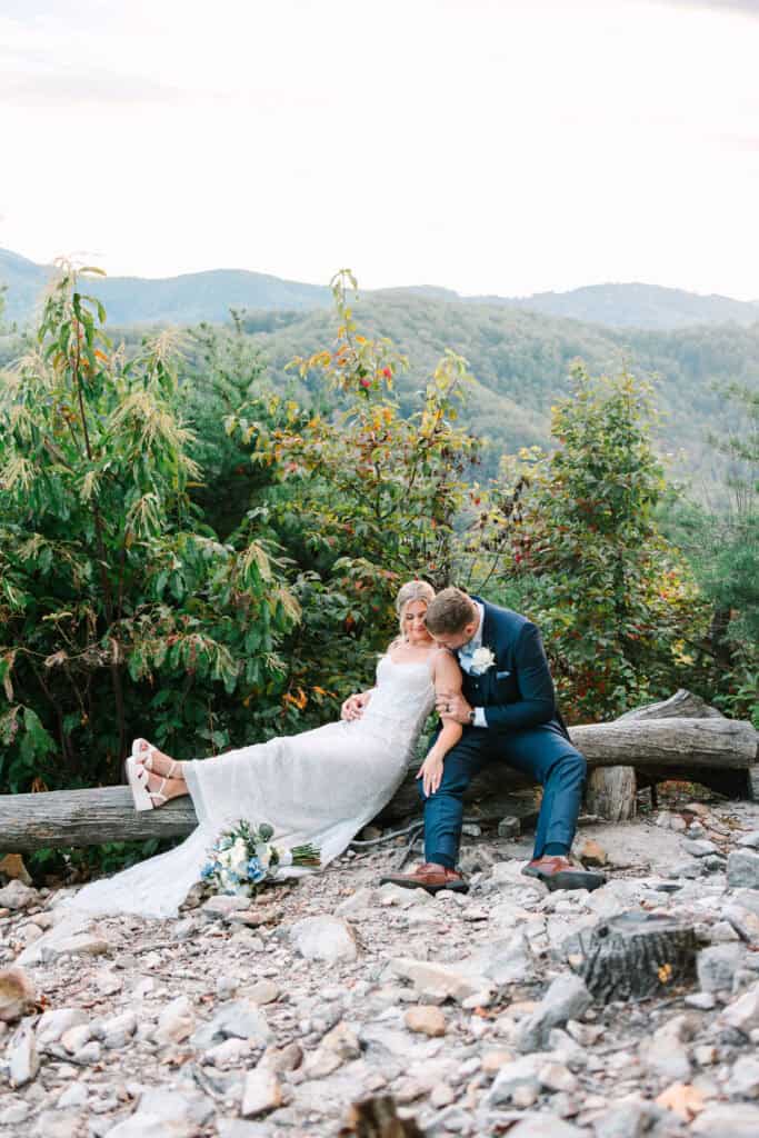 Lauren + Connor Wedding Wide portrait of the couple seated above forested mountain ridges