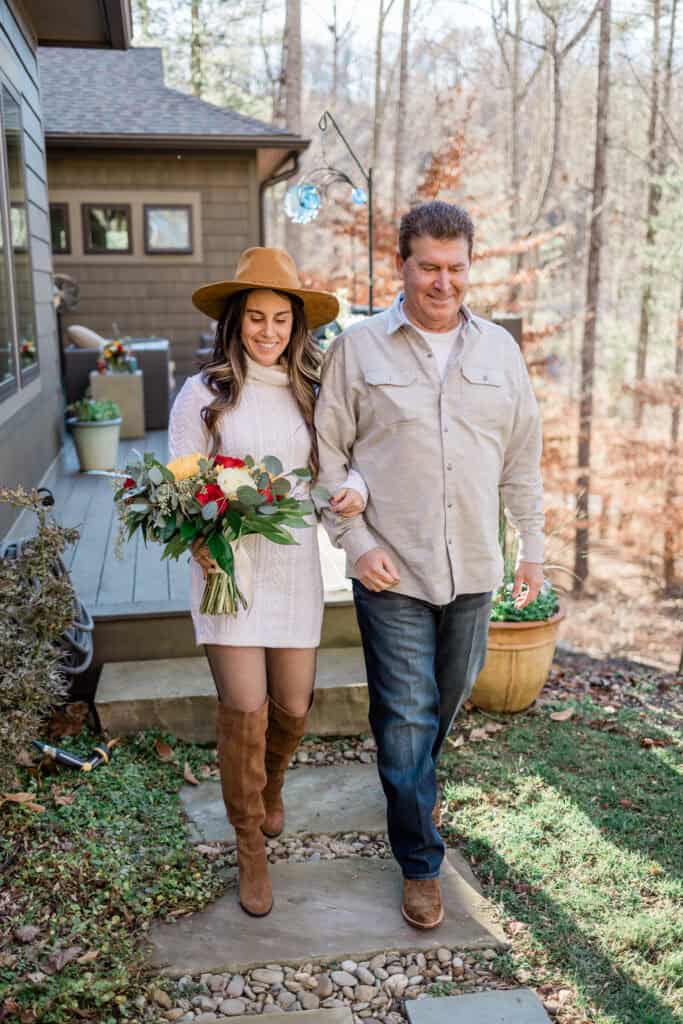 Laura + Steve Elopement Bride in a white sweater dress and tan hat walking to the ceremony