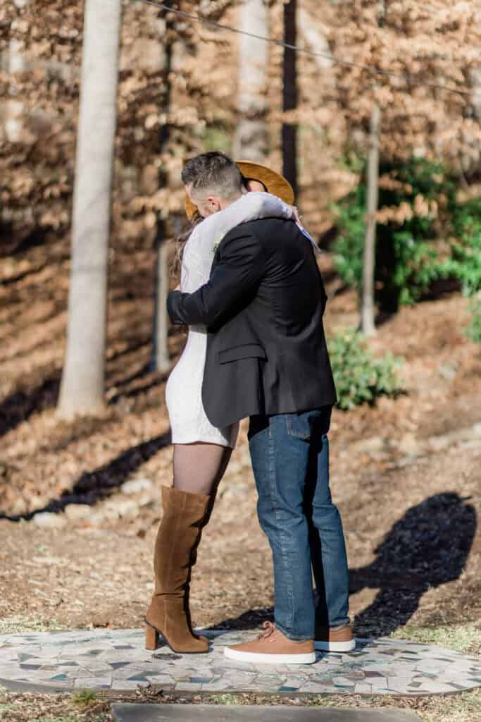 Laura + Steve Elopement First kiss under the trees on the stone patio