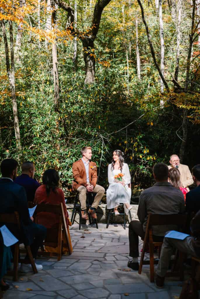 Thaís + Nick Wedding Family seated on the stone patio for a riverside Elkmont wedding ceremony