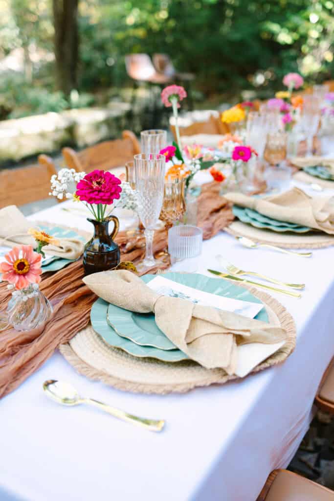 Thaís + Nick Wedding Pink and orange flowers beside teal plates on the reception table