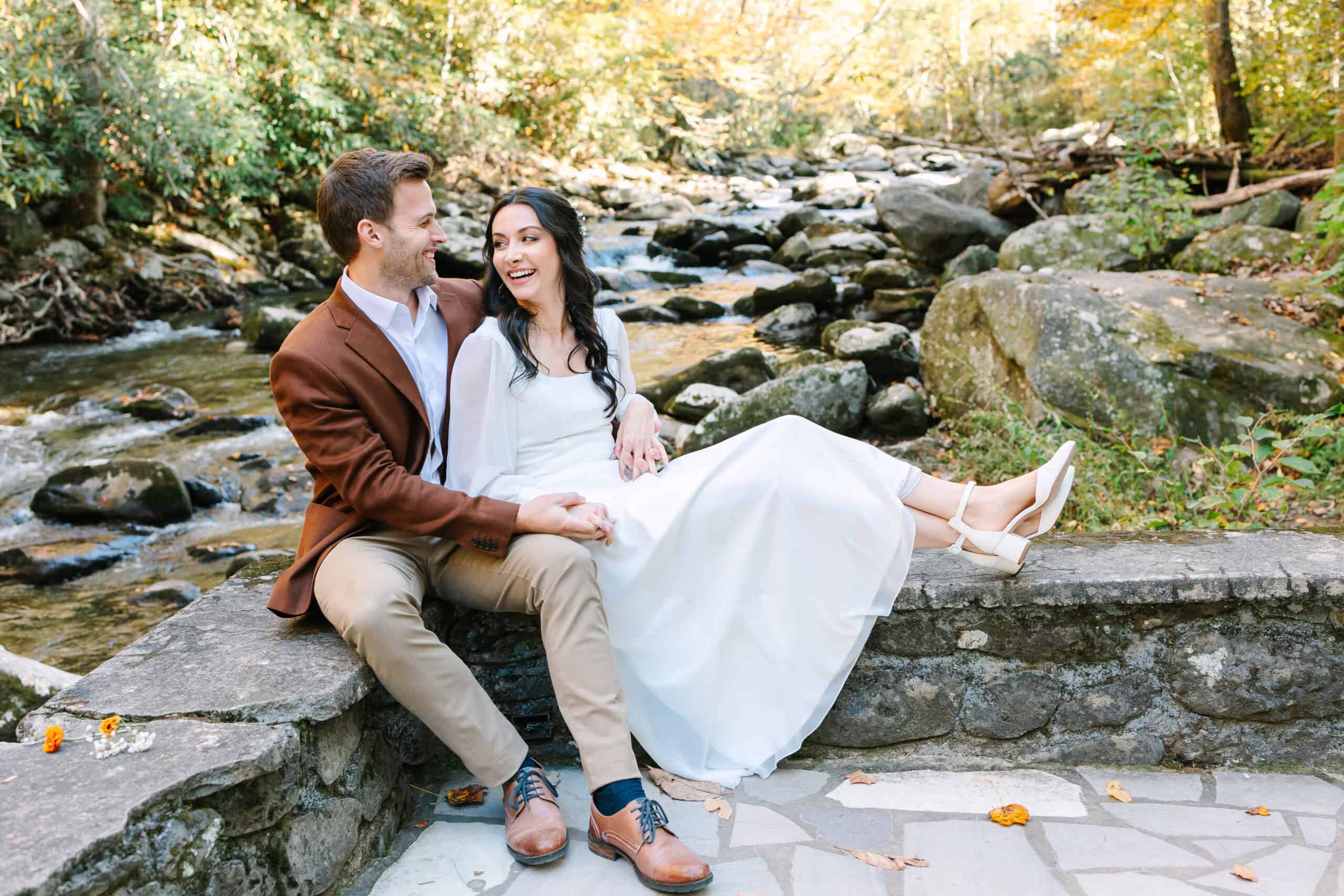 Couple laughing together on a stone ledge by the Little River