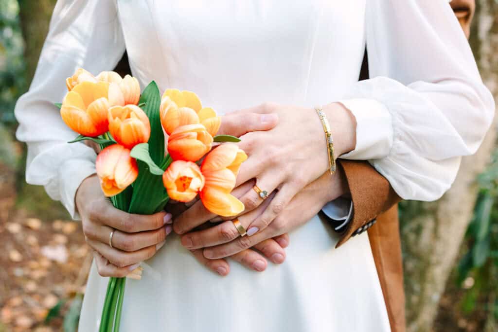 Thaís + Nick Wedding Bride holding an orange tulip bouquet against her white dress