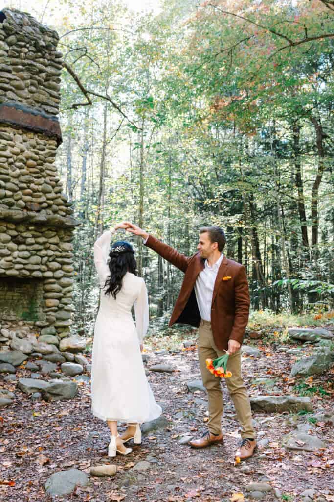 Thaís + Nick Wedding Groom twirling the bride beside an old stone chimney in Elkmont