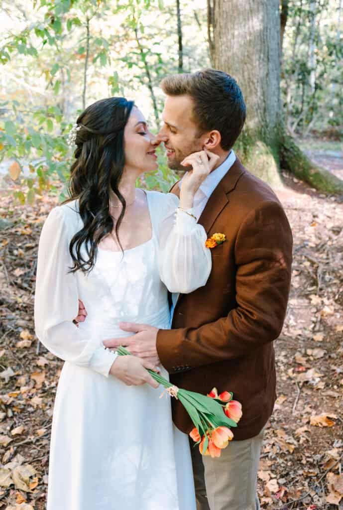 Thaís + Nick Wedding Groom kissing the bride on the cheek among tall trees