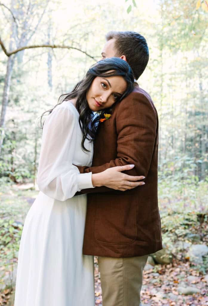 Thaís + Nick Wedding Bride resting her head on the groom with fall color behind them