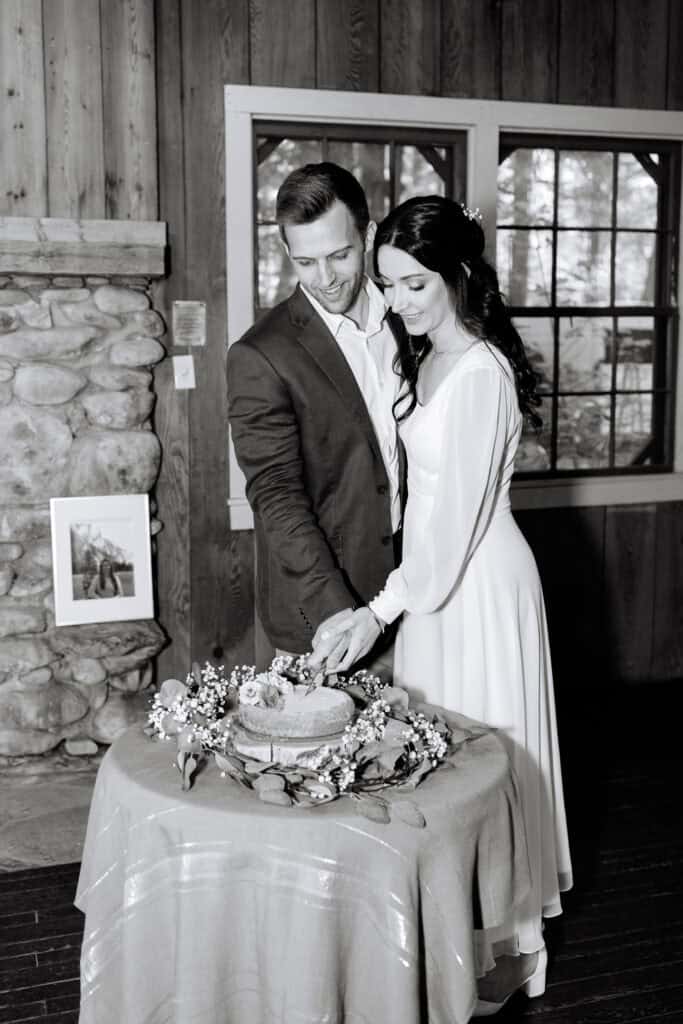 Thaís + Nick Wedding Black and white photo of the couple cutting their cake inside Spence Cabin