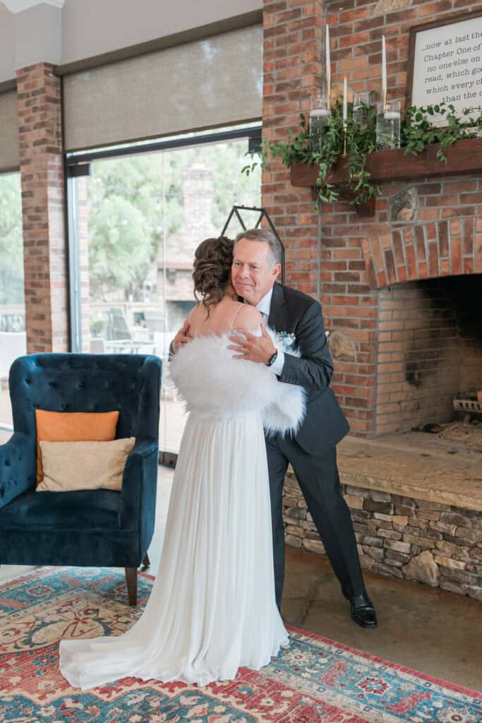 Sarah + Jake Wedding Bride hugging her dad in front of the stone fireplace